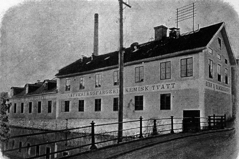 Historisk bild på Yllefabriken i Norrtälje. Yllefabriken ligger längs Norrtäljeån och är en stor byggnad i två våningar.