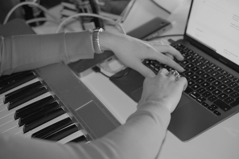 Bilden visar en keyboard och en dator med händer som skriver på tangentbordet