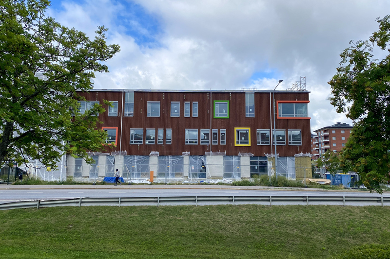 Skola med träfasad och fönsterkarmar i rött grönt och gult under uppbyggnad.