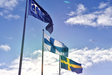 Norrtälje kommuns flagga, den finska flaggan och den svenska flaggan som vajar i luften.