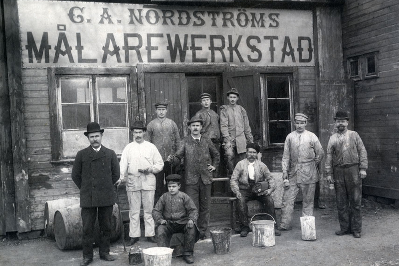 Historisk svartvit bild på personalen på Nordströms målareverkstad. Bilden visar 10 män utanför affären.