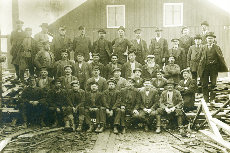 Arbetarna vid Ångsågen. Närmare 40 män syns på bilden, uppställda på fyra rader.