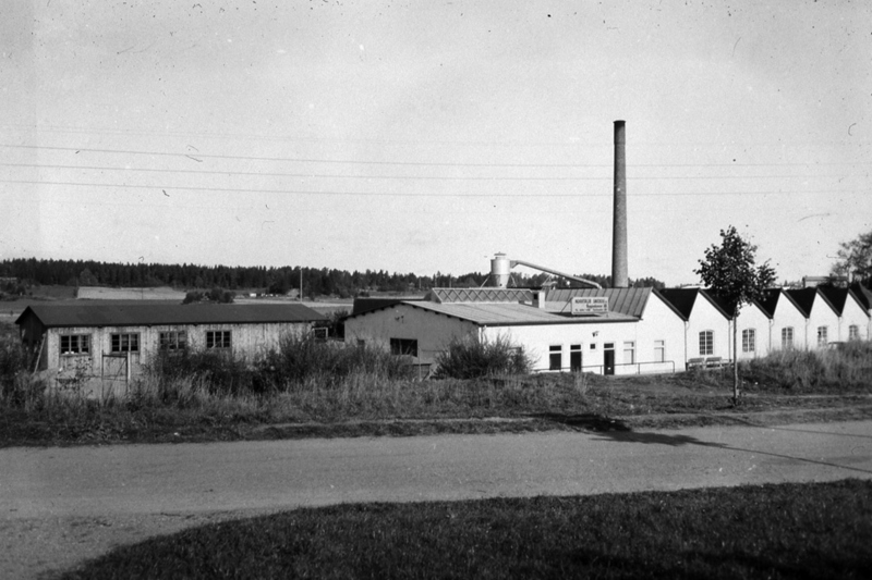 Norrtälje Snickerifabrik. En låg vitbyggnad med hög skorsten