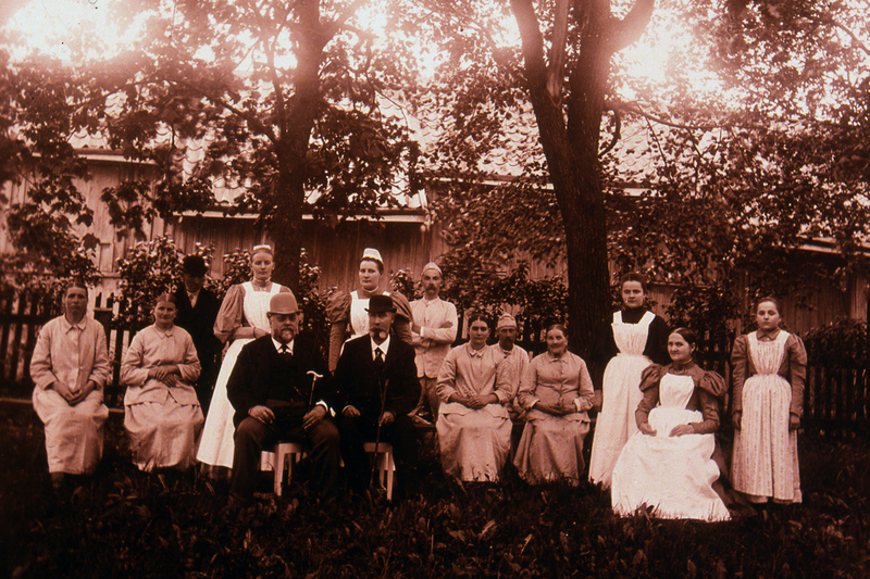 Historisk bild på personal som arbetade vid lasarettet. Fem män och nio kvinnor.