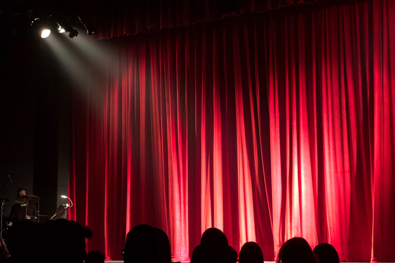 Bild av en scen med en röd ridå och en spotlight