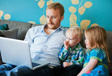 Pappa med två barn och en laptop