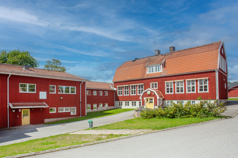 Röd skolbyggnad med tegeltak.