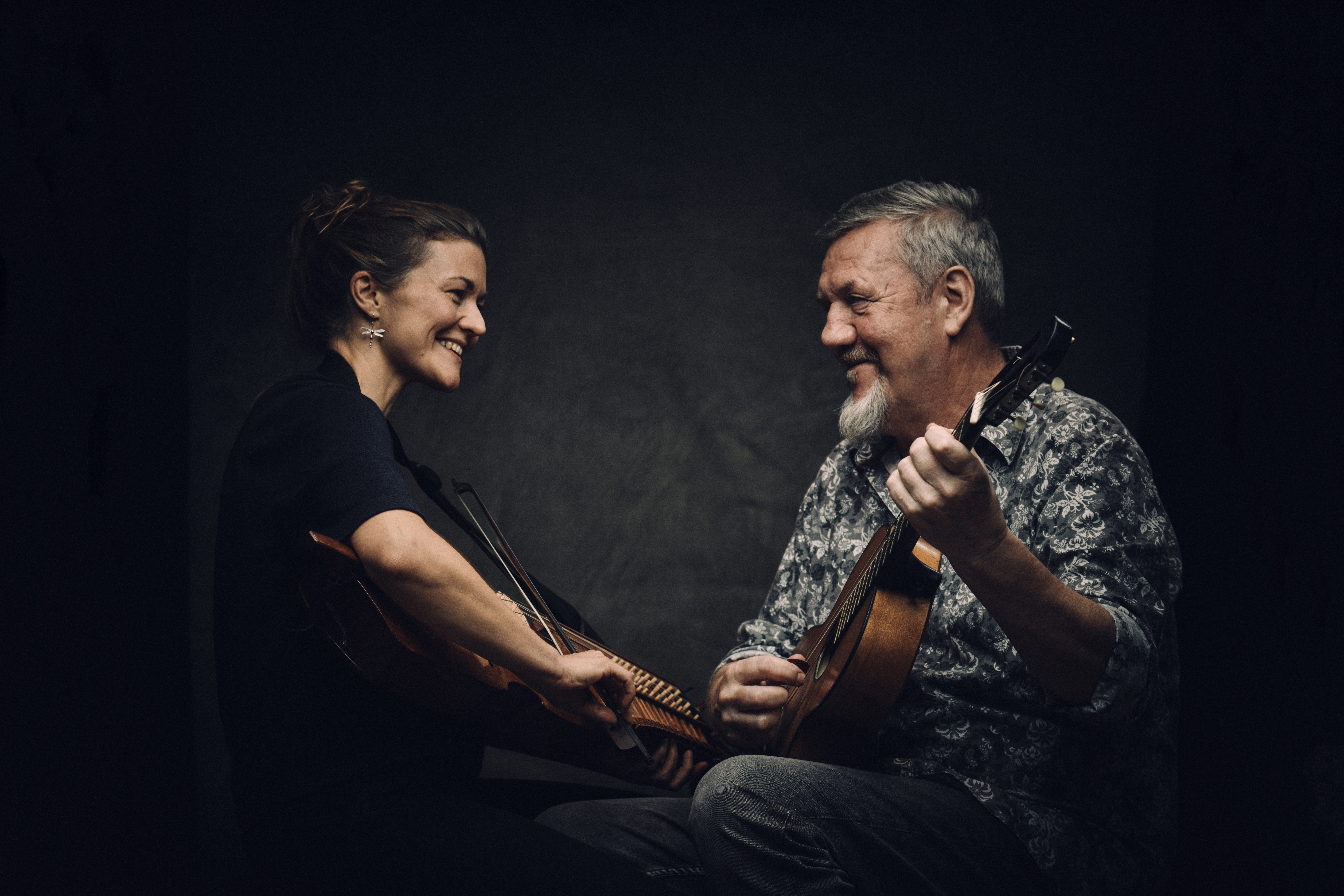 Josefina Paulson med nyckelharpa och Roger Tallroth med gitarr tittar leende på varandra samtidigt som de spelar på sina instrument