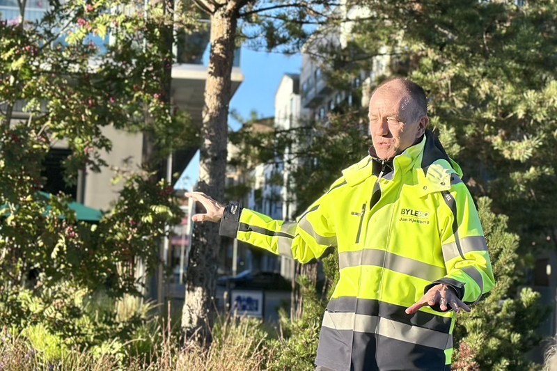 En man i varseljacka står bland klippor och träd och pratar