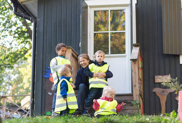 Happy teacher with children outside preschool building