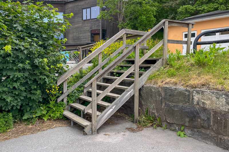 En trappa i tr&auml; som leder fr&aring;n en parkering till en v&auml;g.