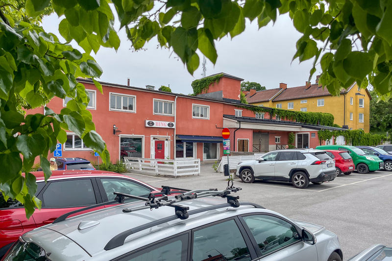 En parkeringsplats full av parkerade bilar framf&ouml;r en byggnad.