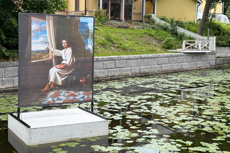 Konstverk som f&ouml;rest&auml;ller en m&aring;lning av en kvinna som m&aring;lar en m&aring;lning. Verket &auml;r placerat i Norrt&auml;lje&aring;n.