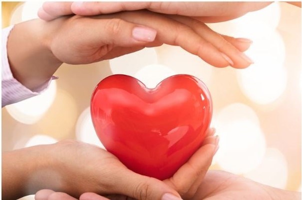 Händer som håller ett rött hjärta.