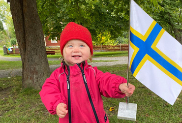Barn håller i sverigefinska flaggan