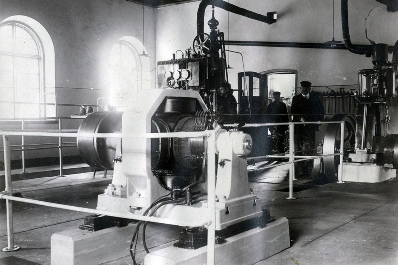 Historisk svartvit bild. Två herrar står inne i industribyggnaden.