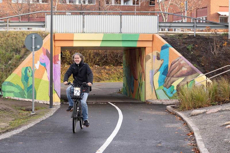 En färgsprakande gångtunnel och en cyklande man med långt hår