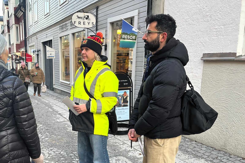 en kvinna och en man står på en gata och pratar med människor