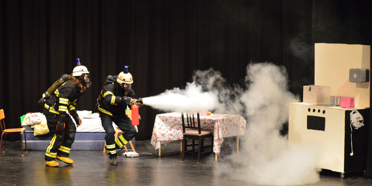Teaterföreställning med brandmän som släcker brand.