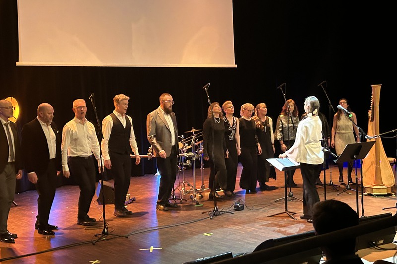 Bild på en scen med fem män och sex kvinnor som sjunger