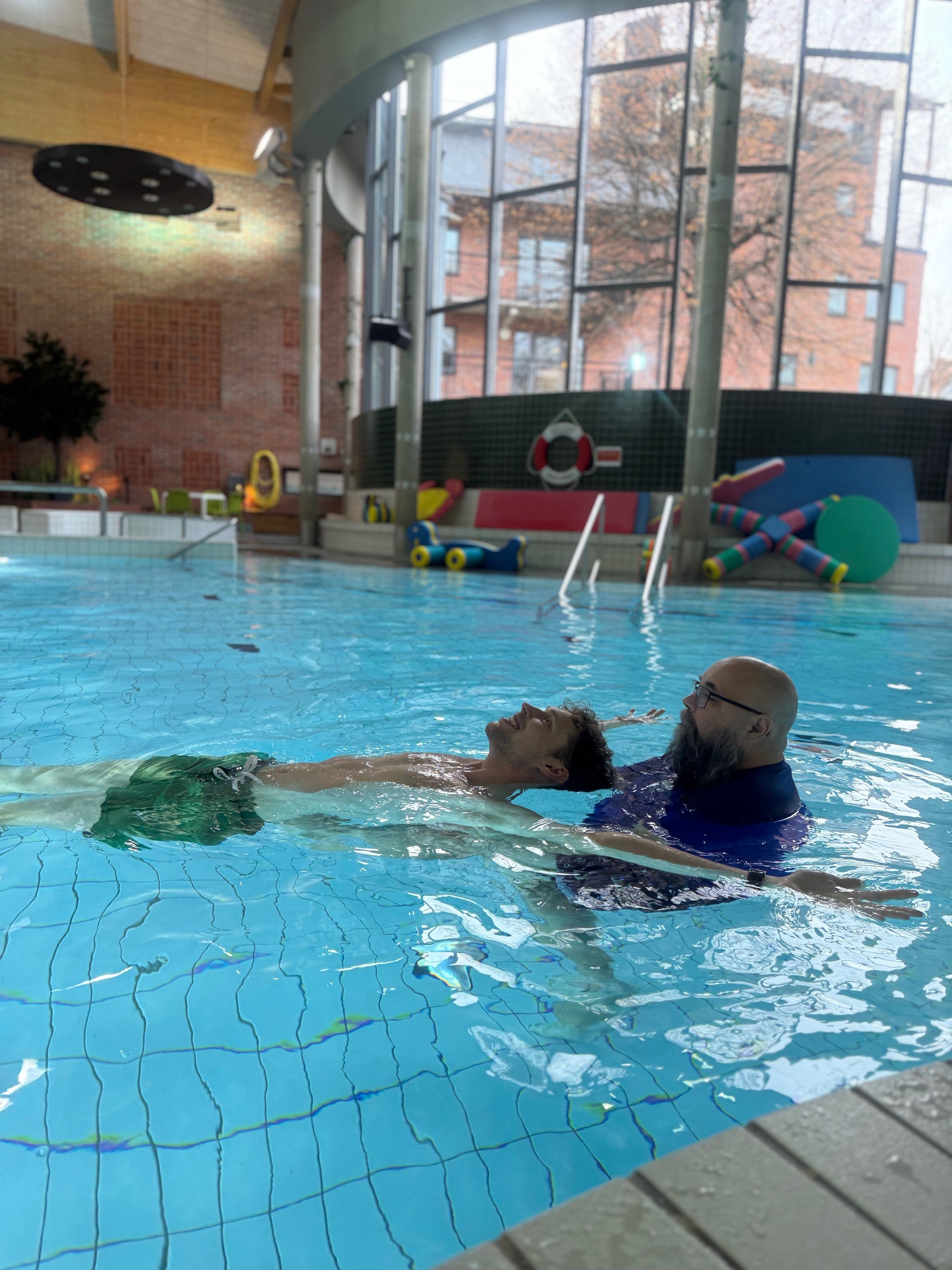 Simläraren hjälper eleven att flyta i ryggläge.