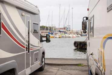 Bild på två husbilar, med en hamn i bakgrunden.