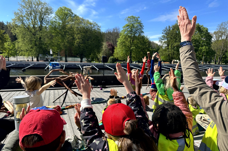 Barn och pedagoger deltar i dansen med uppsträckta händer i luften