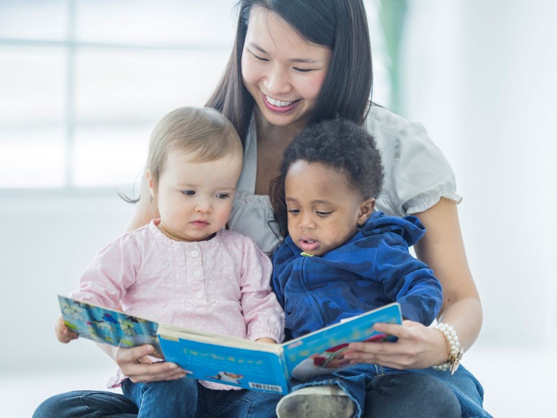 Vuxen som högläser för två barn.