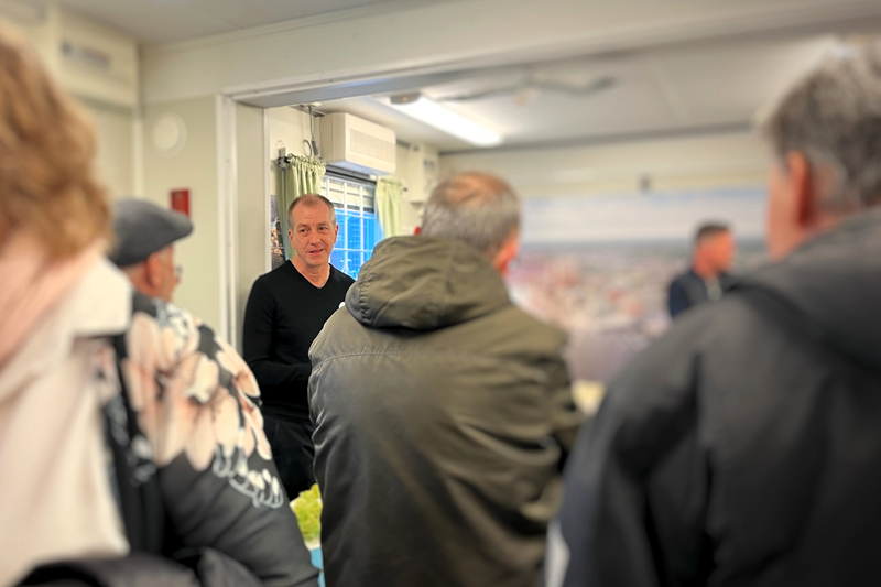 En man håller en presentation av trämodellen över Norrtälje hamn för intresserade åhörare