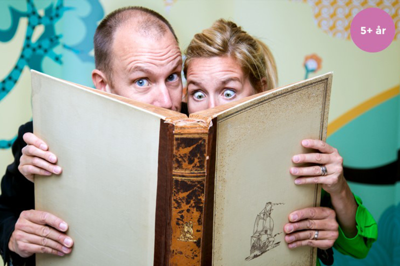 En man och kvinna håller en stor bok framför ansiktet så endast ögonen syns. Kvinnans ögon är stirriga och vända ner i boken, mannens ögon ser in i kameran.