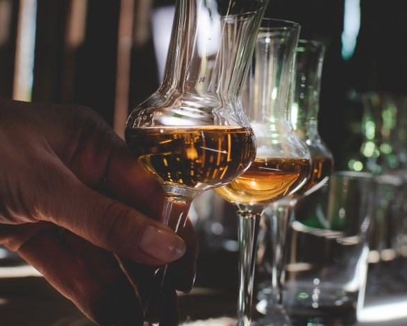 En hand som håller i ett "grappaglas". Fler glas syns i bakgrunden.