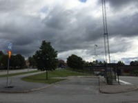 En bild som föreställer en asfalterad yta med en busskur på. Regntunga moln spelar över platsen, som också är Hallstaviks bussterminal.